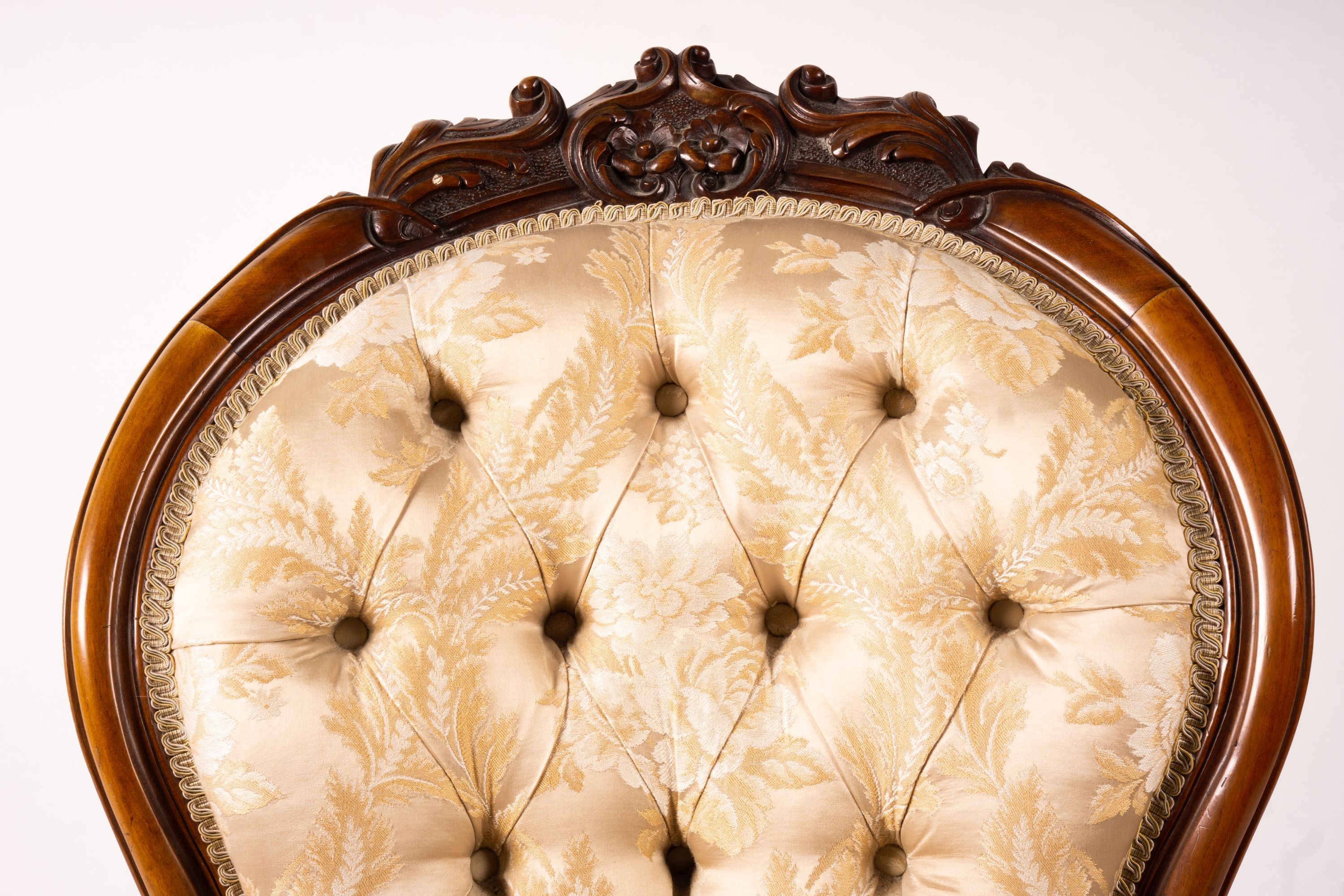 A late Victorian carved walnut three piece salon suite, comprising chaise longue, open armchair and nursing chair